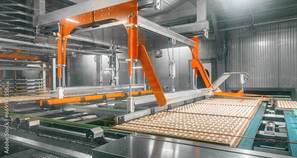 Robot hand moves french croissants into oven after proofing . Modern process food bakery industry production with automatically line conveyor