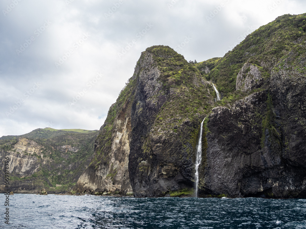 Overview of the magnificent coast of Flores Island. With a waterfall across the steep coast, with beautiful prismatic shapes.