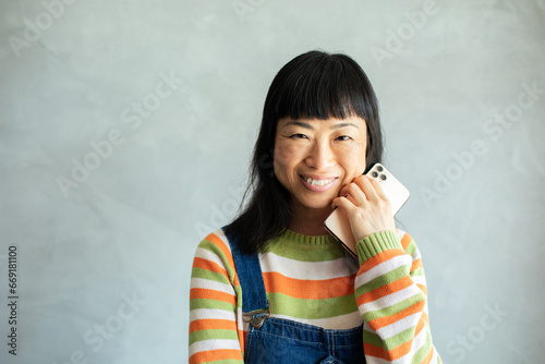 Portrait of a smiling Japanese woman against a grey wall photo