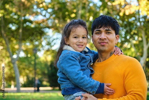 Portrait of happy Ecuadorian father holding his son in a park.