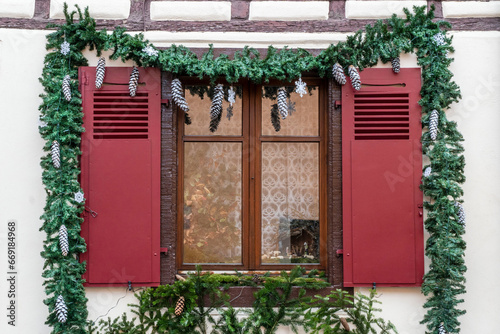 window with red blinders decorated with pine fir and cones for new year