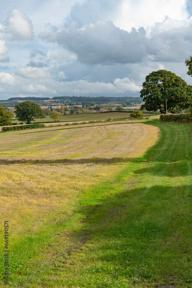 Looking across typical rolling English Cotswold landscape towards a church in the middle distance