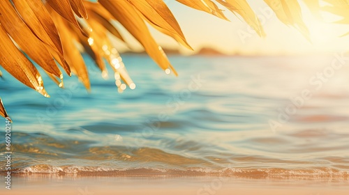 Beautiful background golden sand of the tropical beach, blurry palm leaves, and bokeh highlights on the water