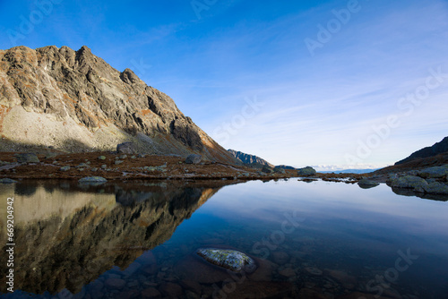 Velke Hincovo pleso, High Tatras, Slovakia. Beautiful landscape of mountain lake and rocky peak and summit. Mirroring reflection of landscape on the water surface. Sunny autumn in the evening.
