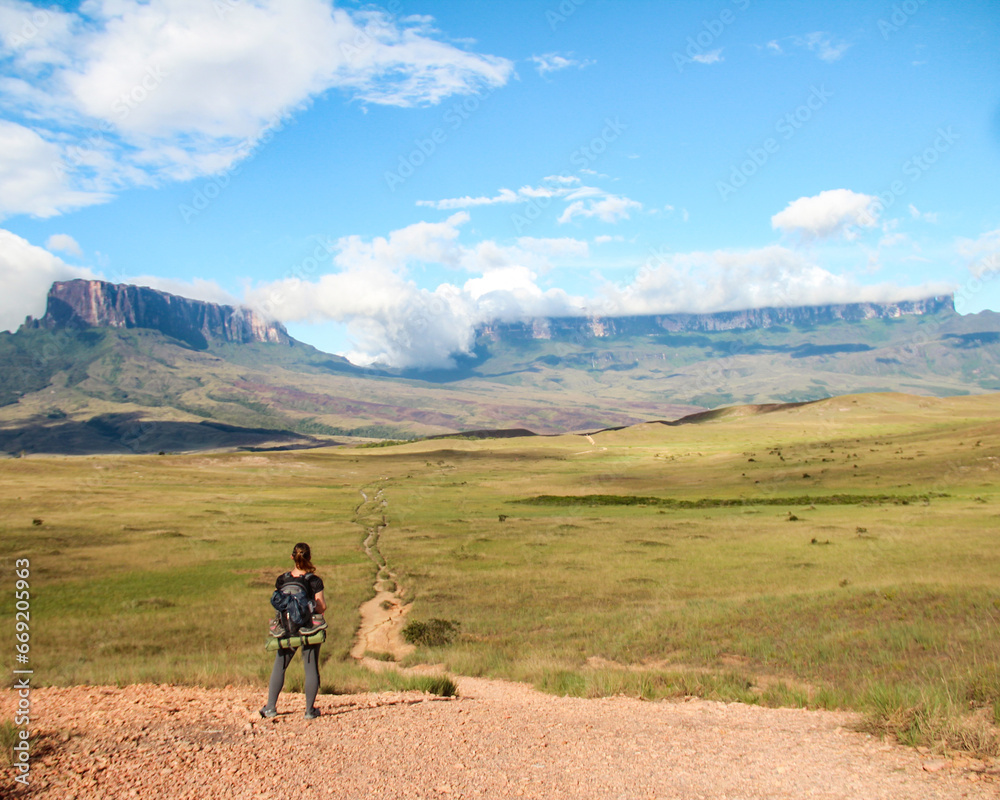 woman with backpack, in trekking to Roraima Mountain, in Venezuela, with mountains in background 