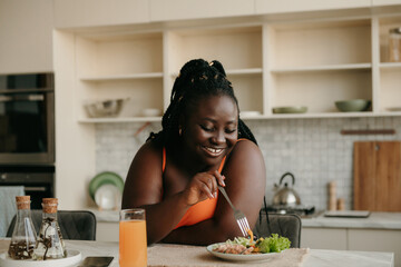 Beautiful curvy African woman enjoying healthy eating for lunch at home
