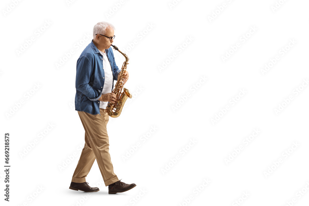 Fototapeta premium Full length profile shot of a mature male musician in casual clothes playing a sax