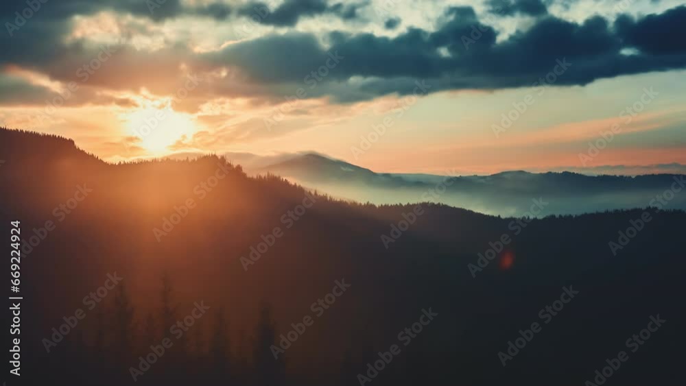 Epic foggy colorful sunrise in alp mountains. Dramatic clouds flow in bright sky, sun glow rising over mountain peak with golden light beams. Beautiful morning nature summer landscape. Time lapse