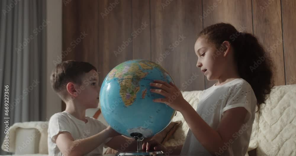Children is studying while sitting at home in rays sunset in room. Kids in morning light sunset with Globe, Cute boy and little girl, technology for school boy, child looks at globe. 4K Children is studying while sitting at home in rays sunset in room. Kids in morning light sunset with Globe, Cute boy and little girl, technology for school boy, child looks at globe. 4K