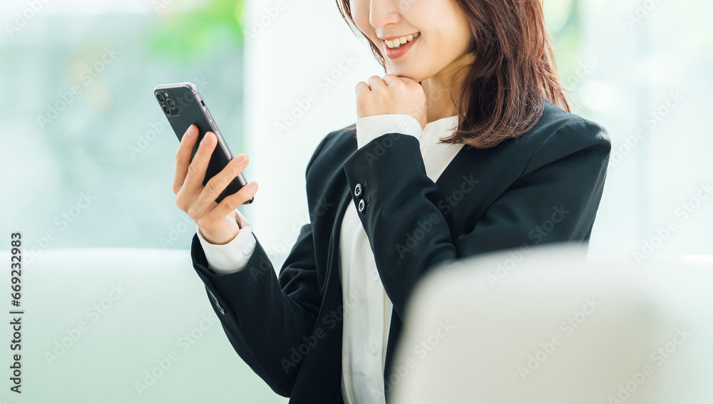 スマホの画面を見る笑顔のビジネスウーマン スマホの画面を見る笑顔のビジネスウーマン