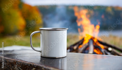 white metal mug by the campfire an empty white metal mug rests on the edge of a table with a softly blurred background