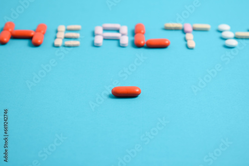 red medicine pill on health word blurred background blue, supplement, vitamin, colorful