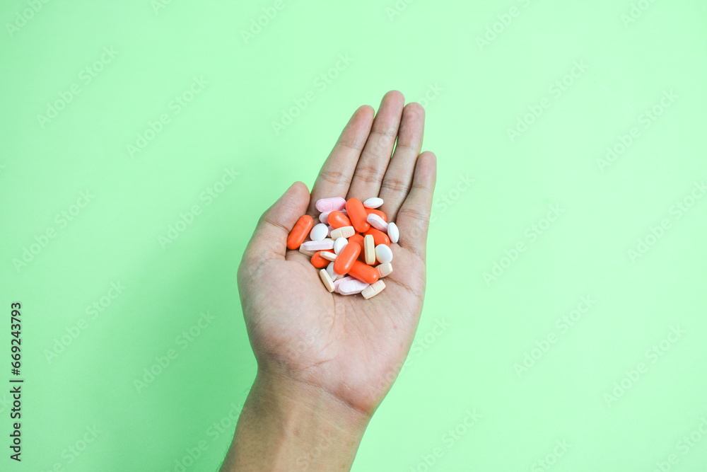 Colorful Medicine pills in man hand on gree background