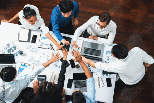 Top view diverse office worker join hand together in office room symbolize business synergy and strong productive teamwork in workplace. Cooperation and unity between business employee. Prudent