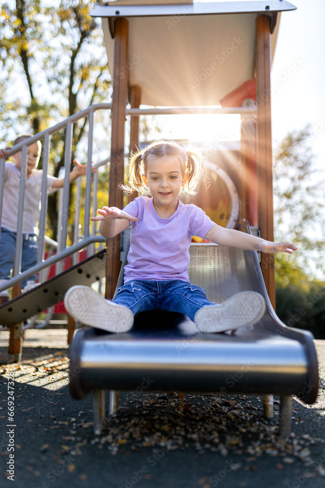 Young girl on slide at the outdoor playground. Active children concept.