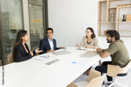 Business colleagues of different ages and races talking at meeting table in office negotiation room, brainstorming on creative ideas, discussing management process, teamwork strategy