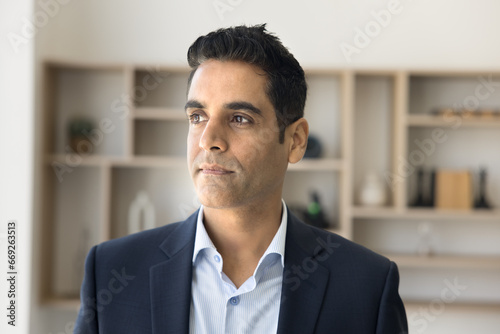 Serious pensive handsome CEO man in formal suit posing in office, looking away in deep thoughts, thinking on future project, business ideas for startup, company management