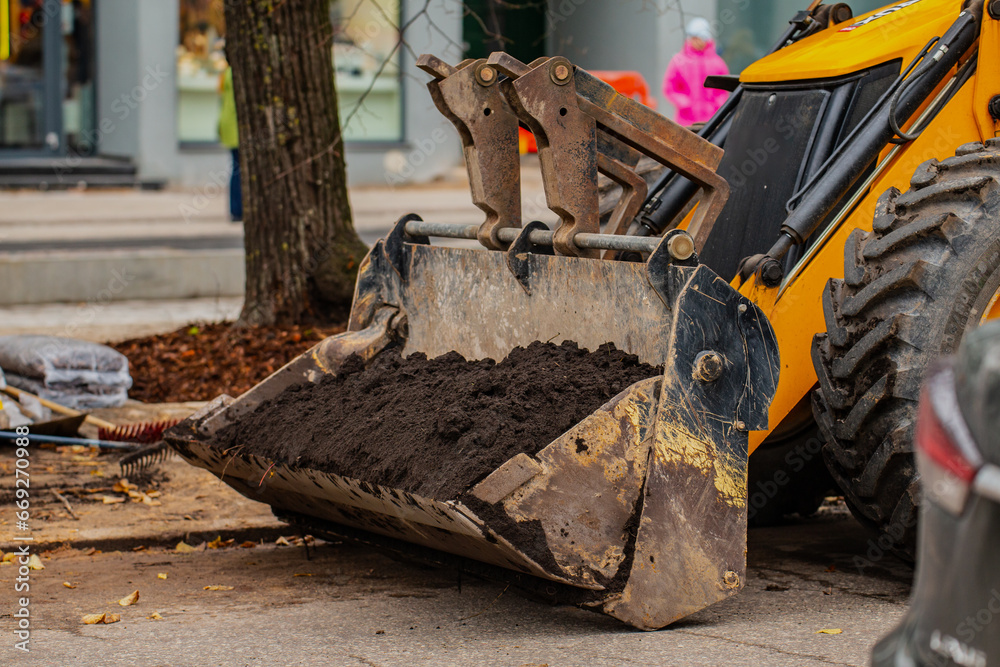 Fototapeta premium Construction earth moving equipment bucket full of earth and rocks in the construction in the city