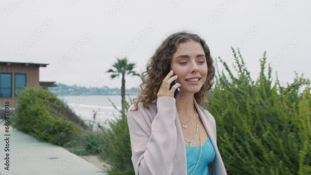 Portrait of friendly curly lady walking with smartphone 4k. Closeup positive woman in casual clothes talking smartphone in summer park outdoor. Smiling young pretty woman calling mobile phone at ocean Portrait of friendly curly lady walking with smartphone 4k. Closeup positive woman in casual clothes talking smartphone in summer park outdoor. Smiling young pretty woman calling mobile phone at ocean
