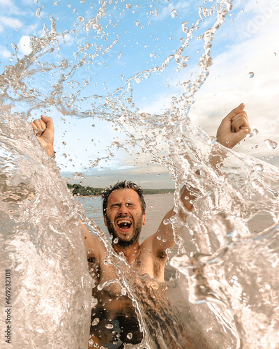 homem de bra  os erguidos cercado de um splash de   gua no Rio Tapaj  s  em Belterera  Par   