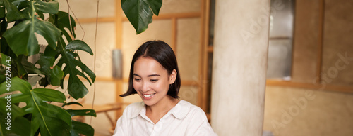 Smiling female manager, freelancer or student sitting with laptop in cafe and working, typing on computer photo