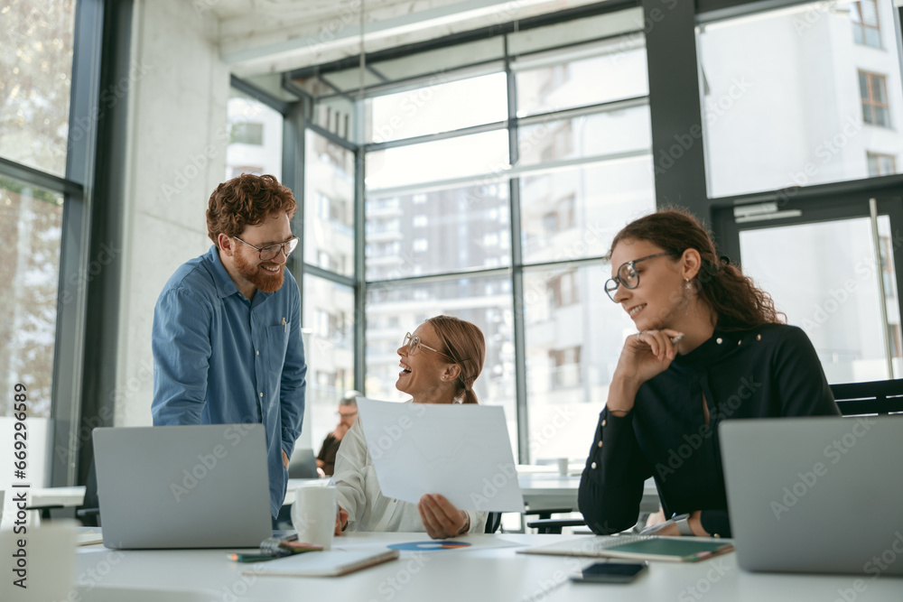 Group of business people discussing something and smiling while sitting at the office table Group of business people discussing something and smiling while sitting at the office table