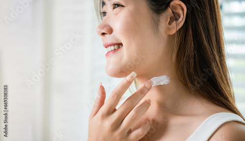 Asian beautiful young woman applying cosmetic cream on neck at home  Happy female apply lotion moisturizer on her neck after shower  Beauty skin care cosmetic protect and nourish skin concept