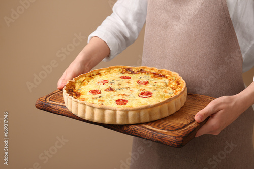 Woman with delicious homemade cheese quiche on beige background, closeup