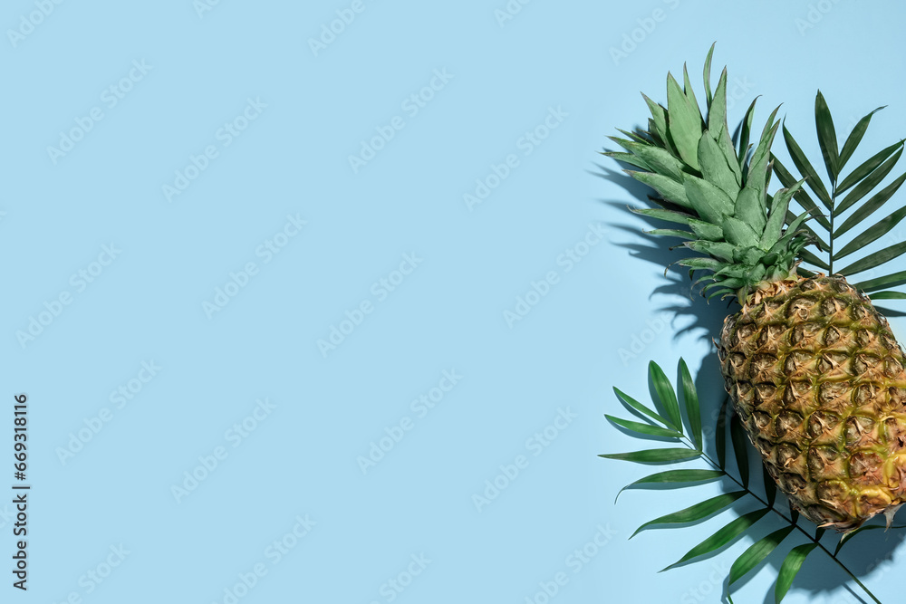 Whole ripe pineapple and green leaves on light blue background, flat lay. Space for text