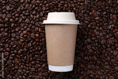 Coffee to go. Paper cup on roasted beans, top view