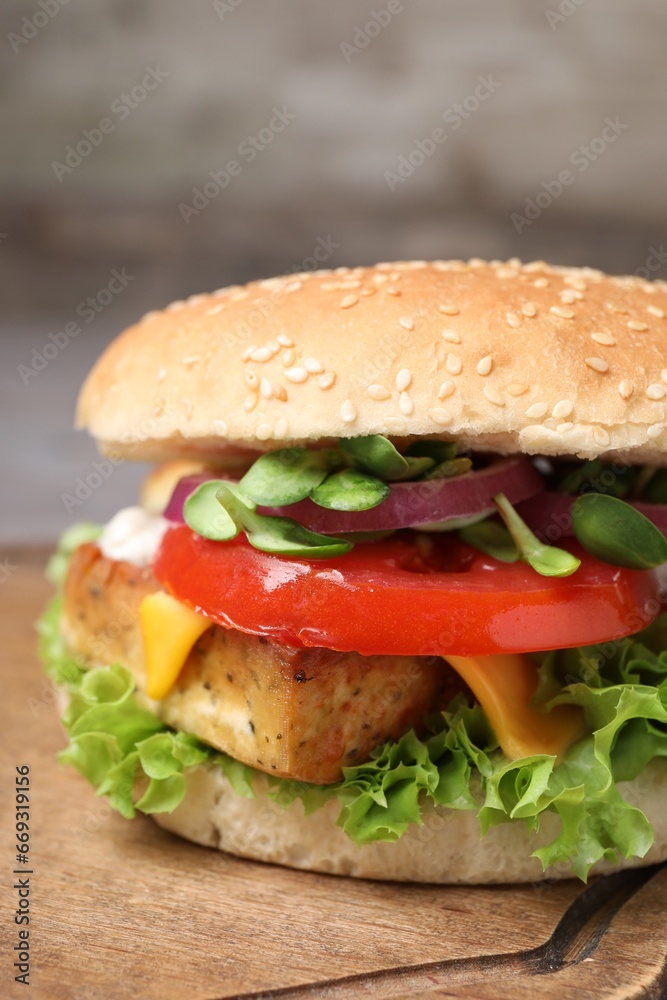 Delicious burger with tofu and fresh vegetables on wooden board, closeup Delicious burger with tofu and fresh vegetables on wooden board, closeup