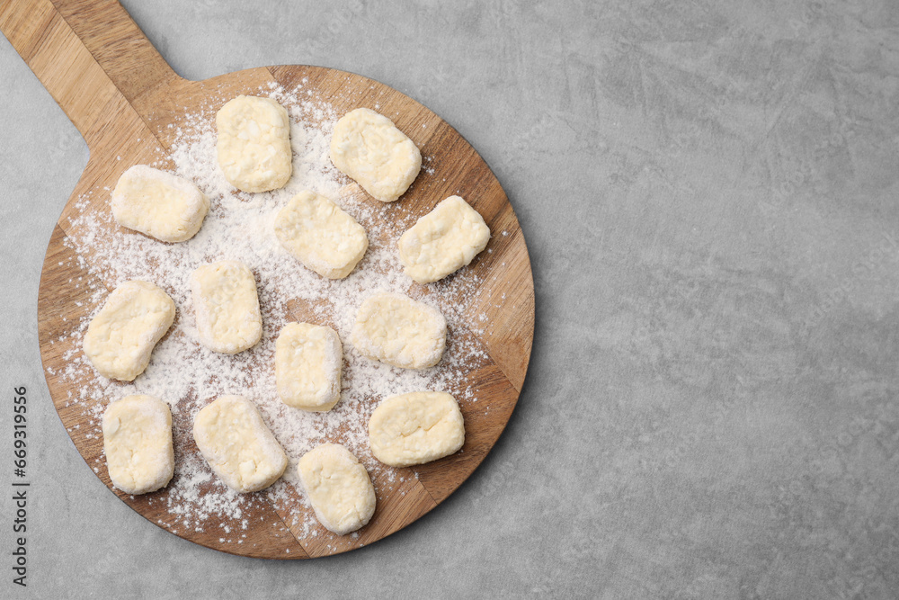 Making lazy dumplings. Board with cut dough and flour on grey table, top view. Space for text