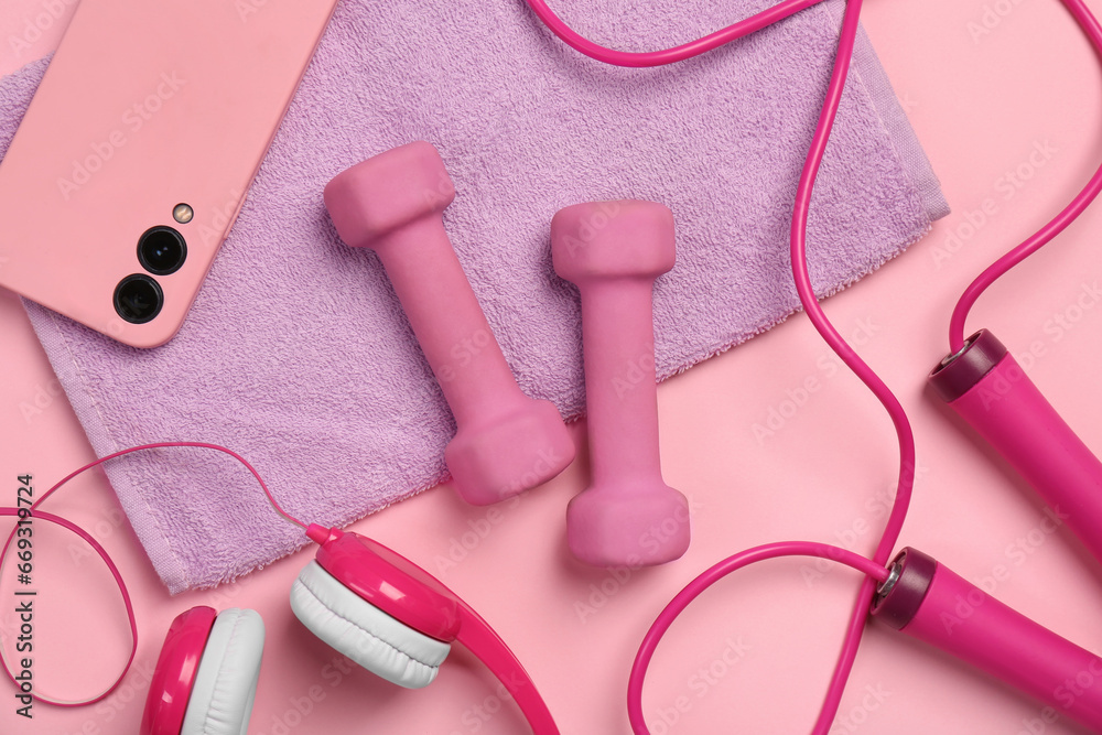 Flat lay composition with dumbbells and smartphone on pink background