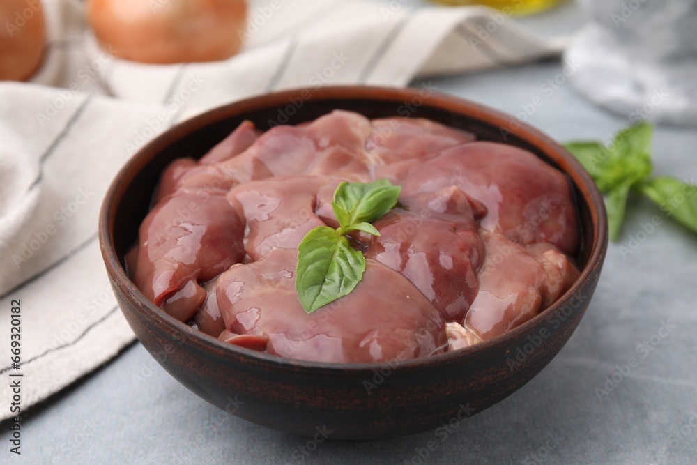 Bowl with raw chicken liver and basil on light grey table Bowl with raw chicken liver and basil on light grey table