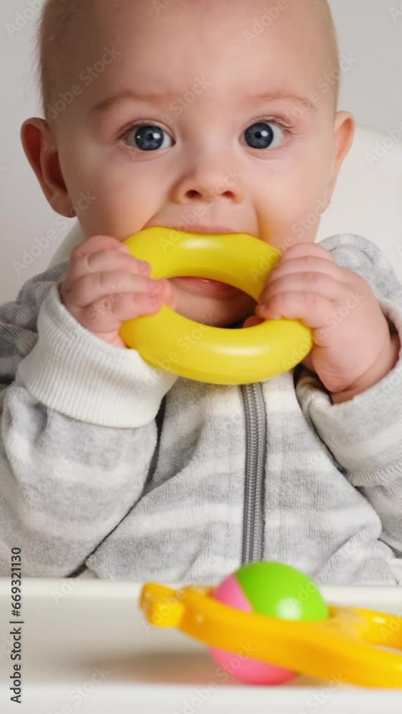 Vertical shot. Baby teething. 8 month old infant gnawing on plastic toy. Vertical shot. Baby teething. 8 month old infant gnawing on plastic toy.