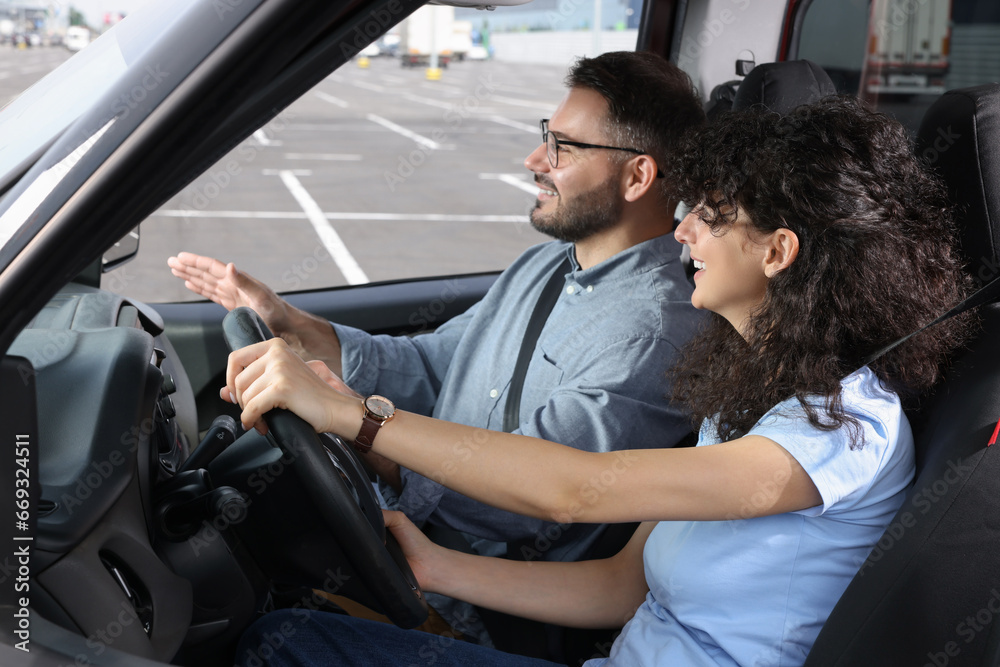 Fototapeta premium Driving school. Happy student during lesson with driving instructor in car at parking lot