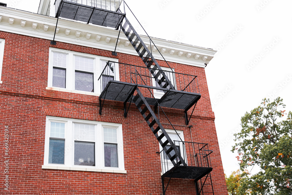 fire escape staircase zigzags outside a brick building, representing escape routes, emergency safety, and architectural aesthetics in the cityscape