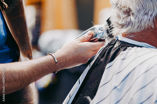 A stylist uses electric clippers to trim and style a clients white hair