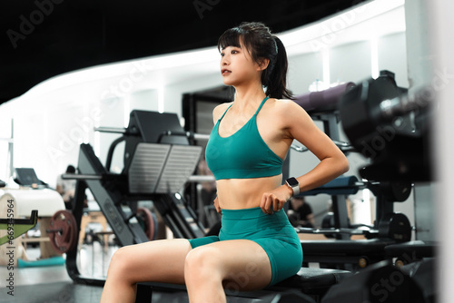 Asian sportswoman is taking a break after training in gym.