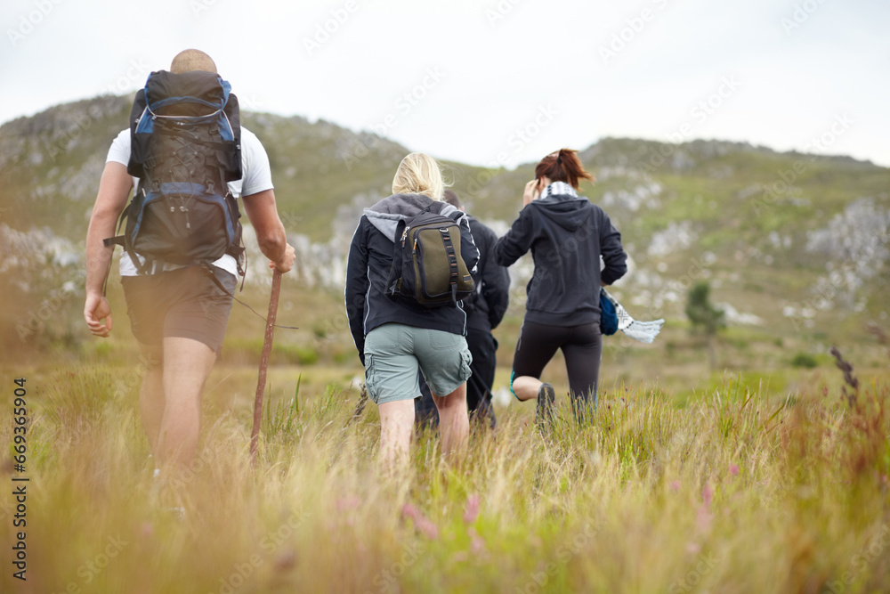 Nature, backpack and group of friends on hiking adventure in mountain with freedom from back. Travel, trekking and people walking in countryside, men and women on natural outdoor journey together.