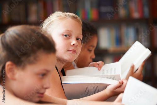 Girl, portrait and reading books in classroom for education, learning and English language, literature or school resources. Face of kid, students or children with novel, textbook or library textbook