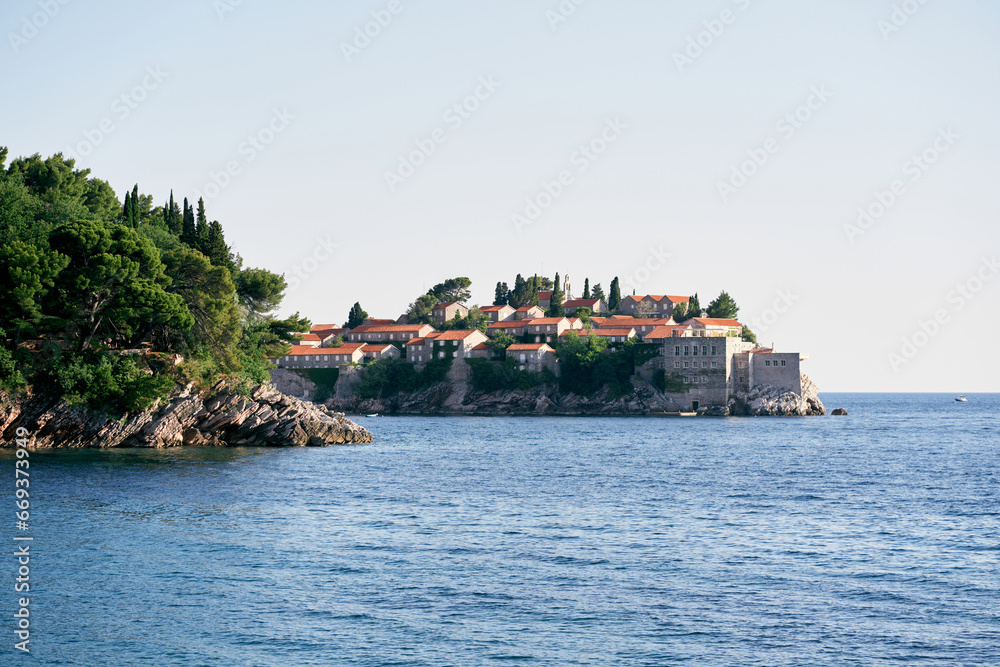 View from the sea to the island of Sveti Stefan behind the green cape. Montenegro