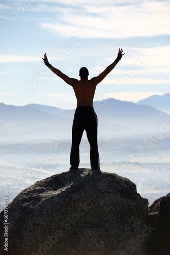 Mountain top, success and back of fitness man stretching arms in nature for performance celebration on sky background. Exercise, freedom and rear view of male athlete with workout, energy or victory