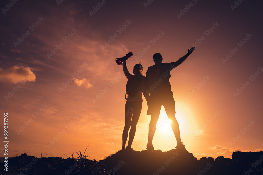 Obraz premium Happy young couple climbs to the top in the mountains near the ocean