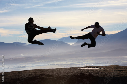 Flying, kick and karate men on mountain top for fitness, training or body, speed or power on sky background. Martial arts, taekwondo or MMA friends in nature with jump, fighting or sports exercise