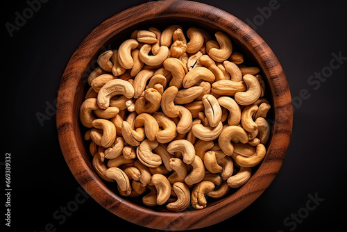 top view of a wooden bowl full of cashew nuts on black background photo