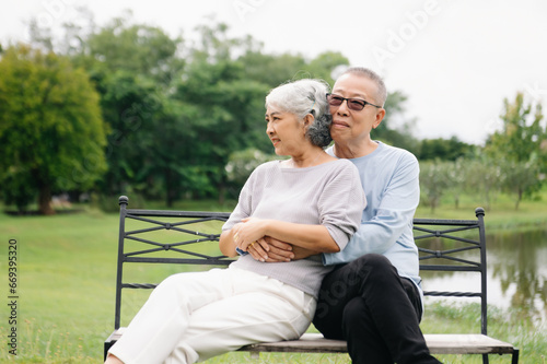 Asian senior couple having a good time. They laughing and smiling while sitting outdoor in park. Lovely senior couple.
