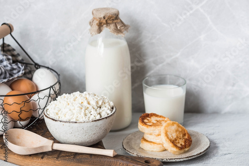 Fresh dairy products, milk, cottage cheese, cheesecakes, eggs in stylish ceramic dishes on a gray background. The concept of natural, dietary nutrition. Useful products.