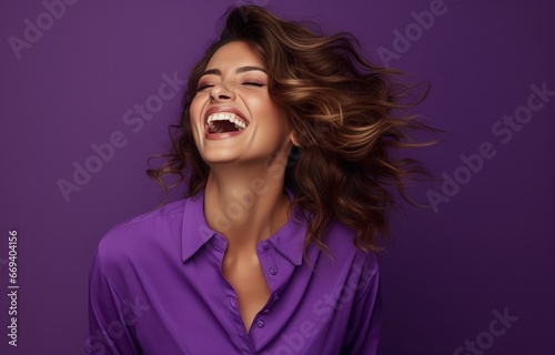 A radiant woman in a purple shirt laughs wholeheartedly against a complementary purple backdrop. Ideal for representing positivity, beauty, and genuine emotion in marketing or editorial content. photo