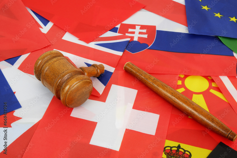 International laws and decisions problems concept. Broken wooden judge gavel on background of many national flags.